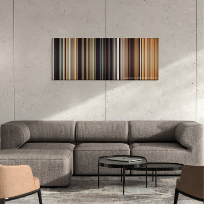 I Origins color palette canvas on a concrete wall above a gray sectional sofa